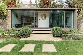 Modern glass-fronted building with steps and landscaped garden.