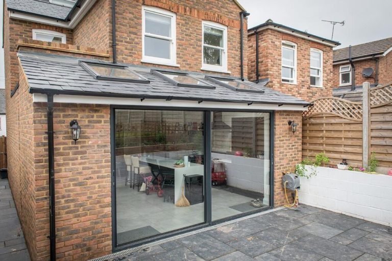 Modern brick house extension with large glass sliding doors and a patio area.