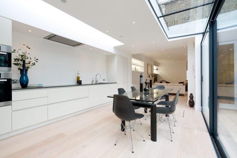 Modern kitchen and dining area with sleek furniture and large glass doors for natural light.