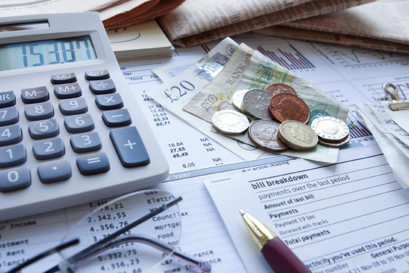 Calculator, coins, banknotes, and financial documents on a desk.
