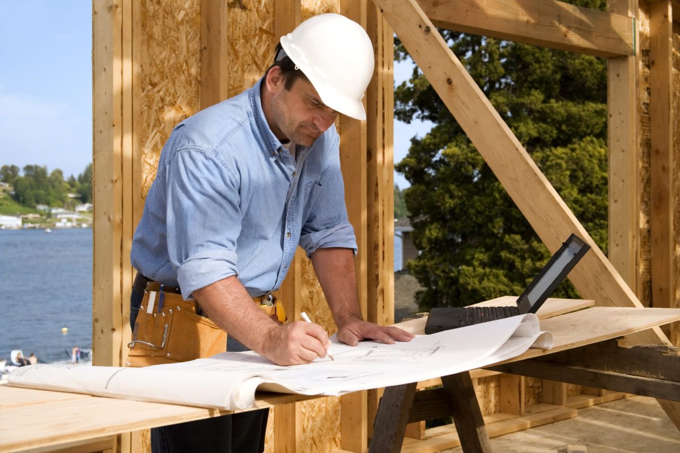 Builder examining blueprints on a construction site, wearing a hard hat.