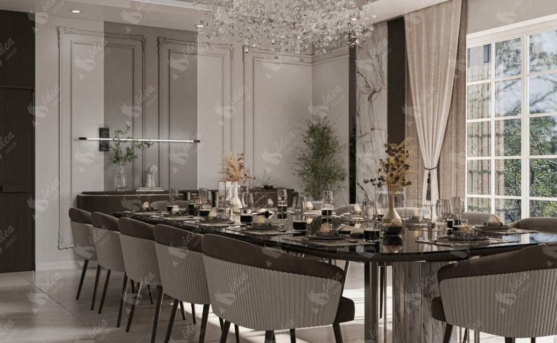 Elegant dining room with a long table set for dinner, featuring modern decor and a chandelier.